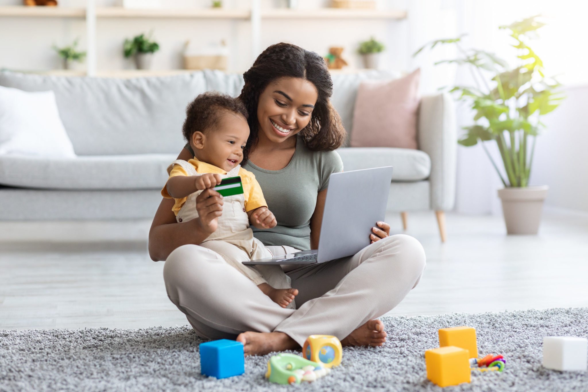 Black Mother With Infant Baby Using Laptop For Online Shopping At Home